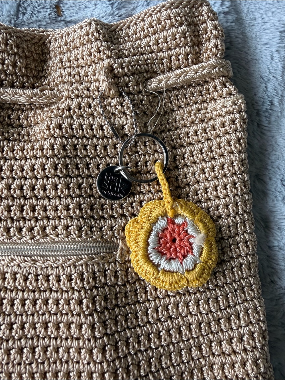 The Sak Crochet Drawstring Bucket Bag in Natural with Yellow and Coral Charm